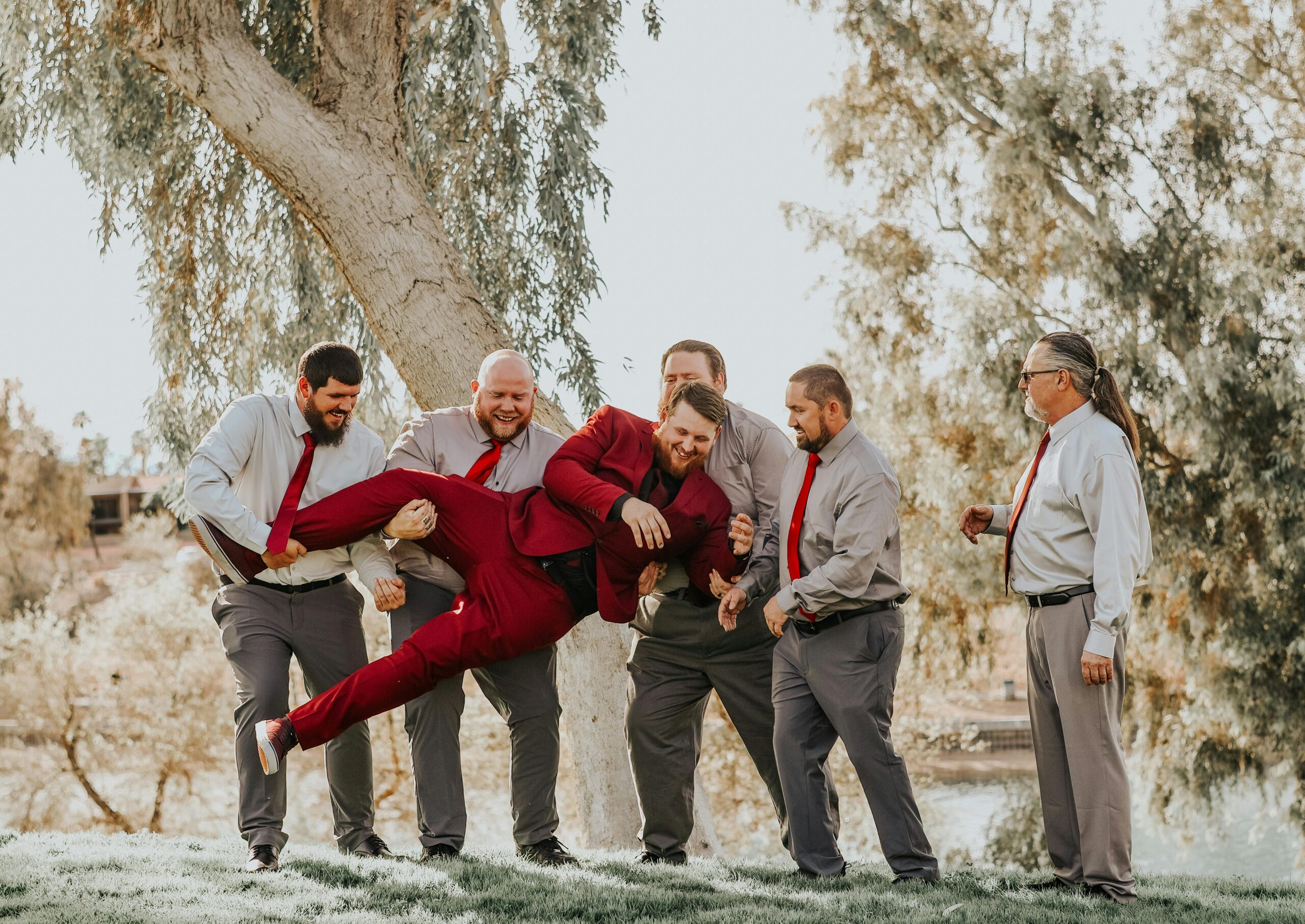 Group of men holding a man in a red suit. Stag do.